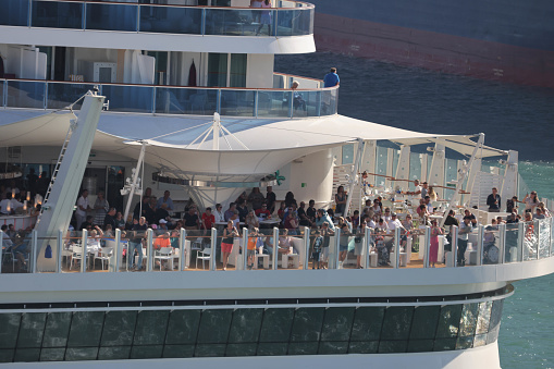 10th June, 2022 - Relaxed, happy and excited cruise ship passengers waving as they sail away from Barcelona Port in the 2021 AIDAcosma a state-of-the-art LNG-powered mega cruise ship