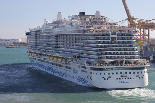 10th June, 2022 - Relaxed, happy and excited cruise ship passengers waving as they sail away from Barcelona Port in the 2021 AIDAcosma a state-of-the-art LNG-powered mega cruise ship