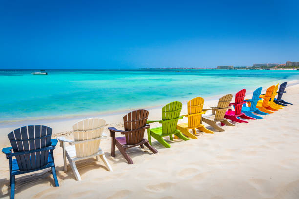 idyllischer strand mit rustikalen adirondack-stühlen in aruba, niederländische antillen - aruba stock-fotos und bilder