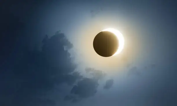 Solar Eclipse with dark blue sky and clouds