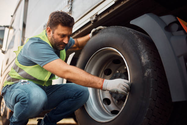 водитель грузовика проверяет безопасность шин перед поездкой. - land vehicle truck semi truck trucking стоковые фото и изображения