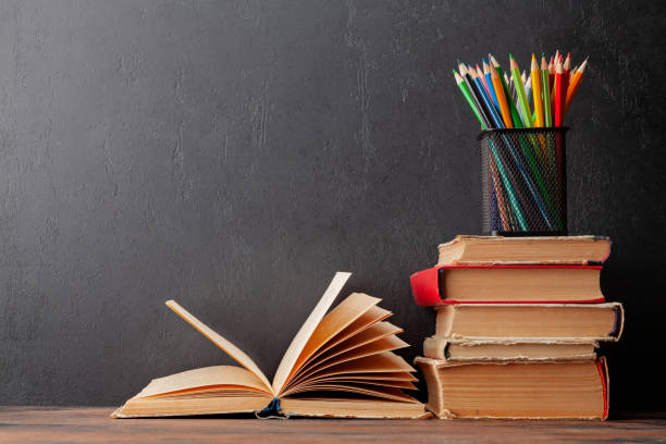 istock Old books on wooden table and blackboard 1412675711