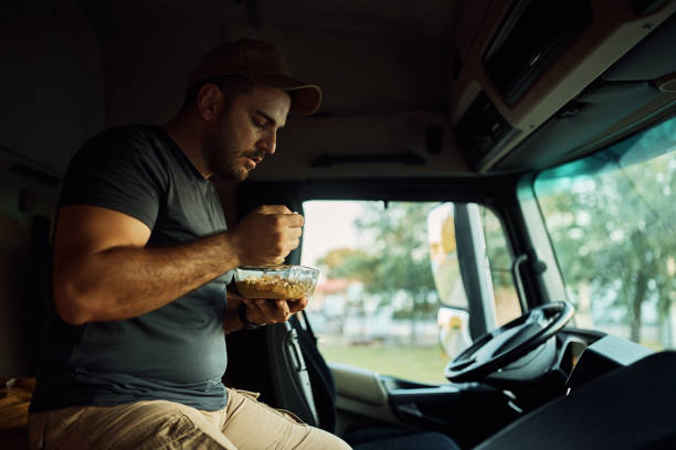 istock Young driver having lunch break in truck's cabin. 1412676652