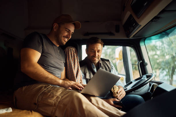 motoristas felizes usando laptop no intervalo do almoço na cabine do caminhão. - truck driver fotos - fotografias e filmes do acervo