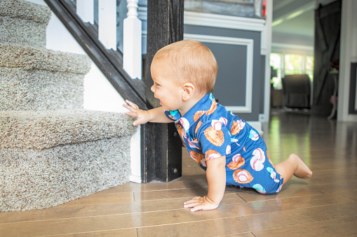 An 11 month old baby boy excited as he crawls towards steps.
