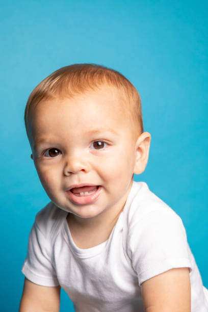 An 11 month old baby boy smiling and showing his baby teeth.
