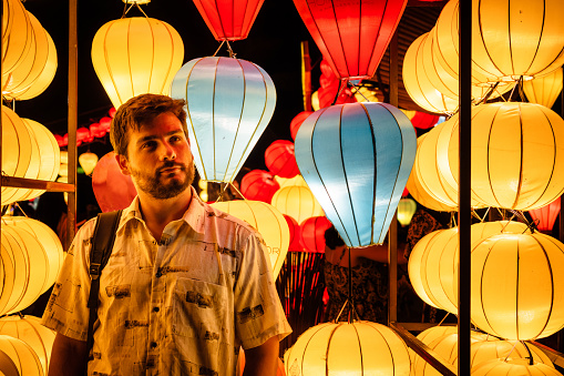 Young tourist surrounded by beautiful paper lanterns in Hoi An, Vietnam. Tourist dazzled by beautiful paper lanterns in Hoi An. Young man surrounded by lanterns in Hoi An old town