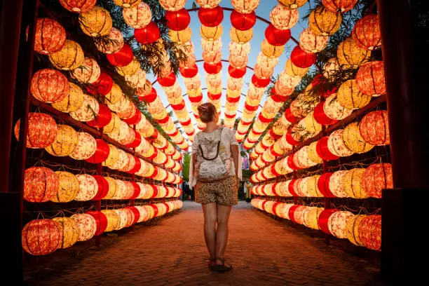 Tourist walking through beautiful arch of lights in Hoi An, Vietnam. Tourist going through archway full of paper lanterns. Beautiful arch of paper lanterns in Vietnam. Lamp lit. Paperlamps. copy-space