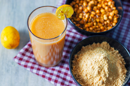 detail of two glasses of orange juice on a white table and a blue background of the mediterranean sea. vacation and health concept. colorful.