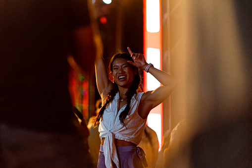 Shot of a Vietnamese girl dancing in the crowd and enjoying the atmosphere at a music festival.