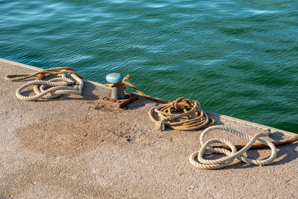 Rusty Mooring Bollard with Ropes in the Port - La Spezia Italy Close-up of a rusty mooring bollard with ropes or hawsers on the quay of the port. Gulf of La Spezia, Liguria, Italy, Europe. mooring line stock pictures, royalty-free photos & images