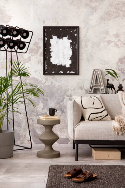 istock The stylish composition at living room interior with mock up poster, grey sofa, coffee table, poster and elegant personal accessories. Loft and industrial interior. Template. 1412683969