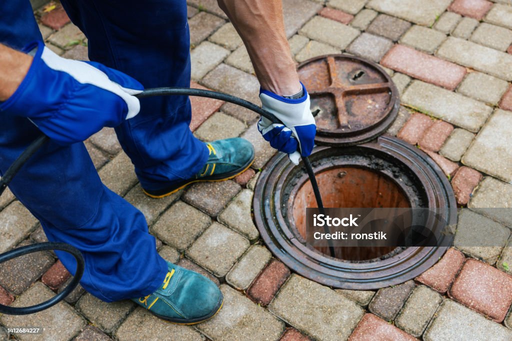 sewer cleaning service - worker clean a clogged drainage with hydro jetting Sewer Stock Photo