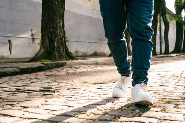 Feet of unrecognizable man walking down the street on a sunny day. Copyspace.