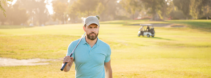 portrait of golfer in cap with golf club. people lifestyle. serious man after game on green grass. summer activity. professional sport outdoor. male golf player on professional golf course.