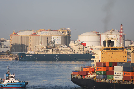 10th June, 2022 - Enagas Liquified Natural Gas (LNG) storage tanks at Barcelona port in Catalonia with container ships sailing by.