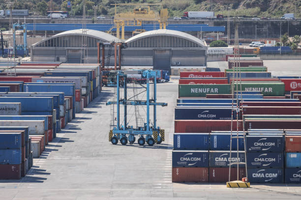 Shipping containers being loaded/unloaded at Barcelona port by automated straddle carriers allowing precise stacking and optimisation of shipping containers stock photo