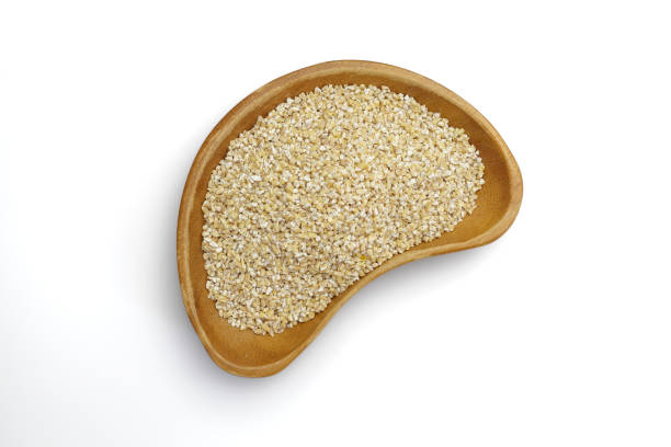 Barley grits in a wooden bowl on  white