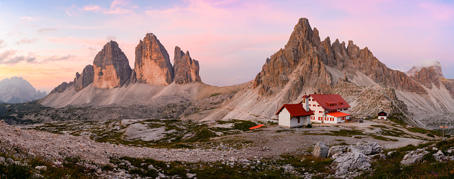 Stunning panoramic view of the Three Peaks of Lavaredo, (Tre cime di Lavaredo) Mount Paterno and a refuge during a beautiful sunset.