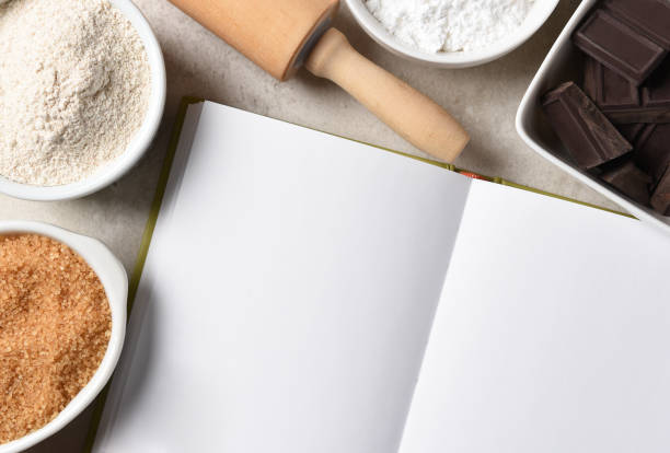 istock Baking Still Life. Blank pages of an open recipe book surrounded by a rolling pin, bow, with flour, sugar and baking chocolate. 1412697421