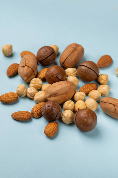 Various nuts scattered on a light background. Almonds, hazelnuts, pecans, macadamia in a pile close up. The concept of healthy eating and snacking stock photo