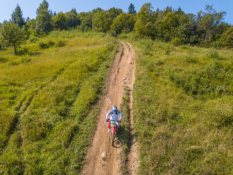 Ukraine, Carpatian - July 26, 2018: Enduro athlete on a dirt path on a sunny summer day. Aerial view
