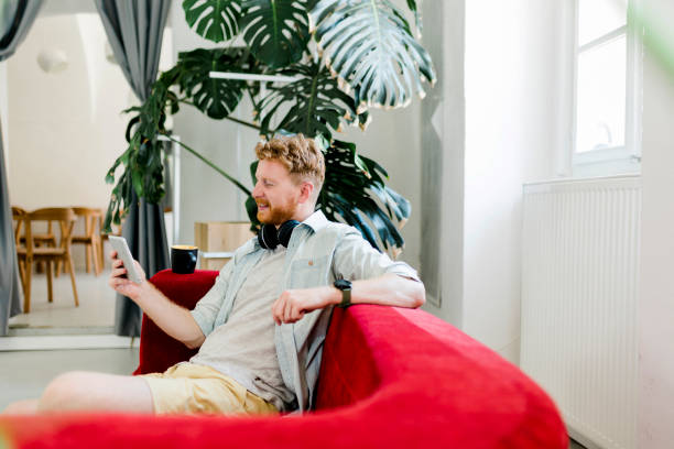 istock Mature ginger businessman drinking coffee and working on digital tablet at home 1412700618