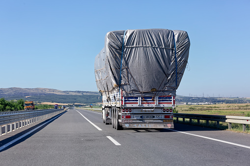 Istanbul, Turkey - Jun 09 2021: Truck with excessive load on the highway road. Back view. Sunny summer day on the asphalt.