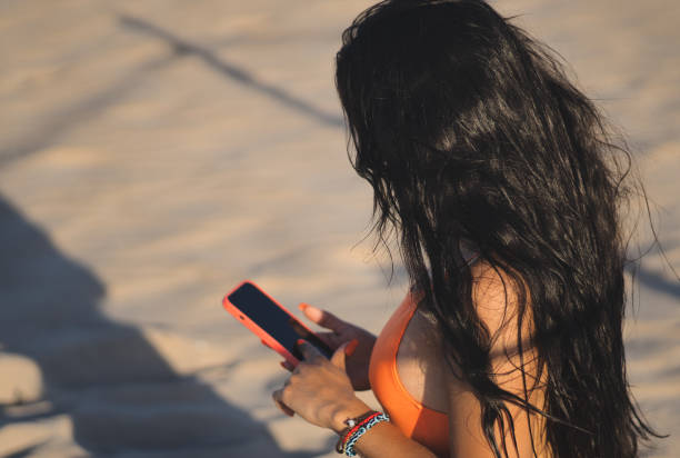 unrecognizable muslim young woman using smartphone on the beach.