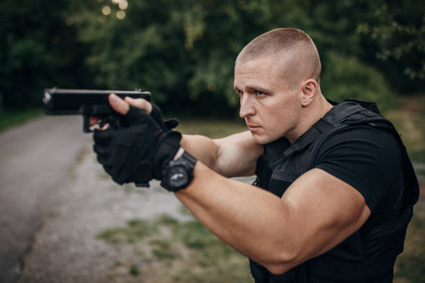 Swat team soldier with a gun Portrait of a SWAT team soldier standing outdoors and aiming with a handgun. soldier grave stock pictures, royalty-free photos & images