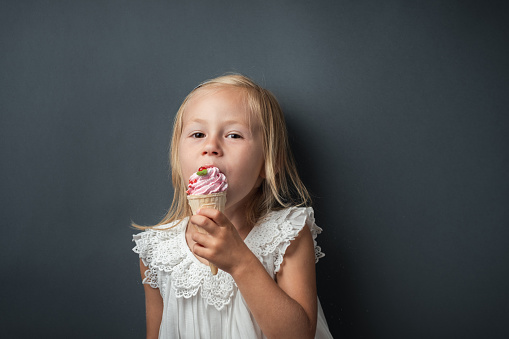 Lovely girl eating ice cream on white