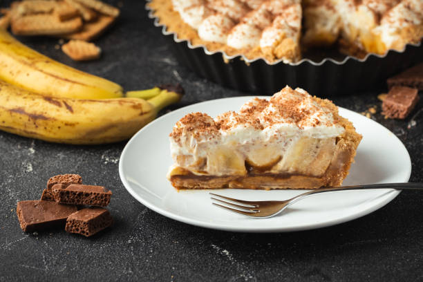 bolo banoffee com recheio de banana e caramelo polvilhado com chocolate escuro ralado no fundo de concreto preto. torta tradicional inglesa - cream filling - fotografias e filmes do acervo