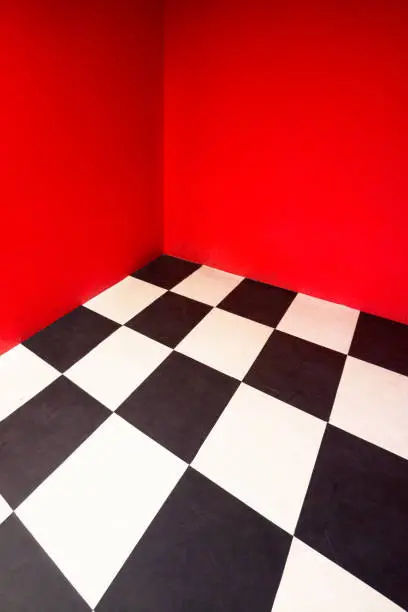 Photo of Empty room with Checkered floor and red painted wall.