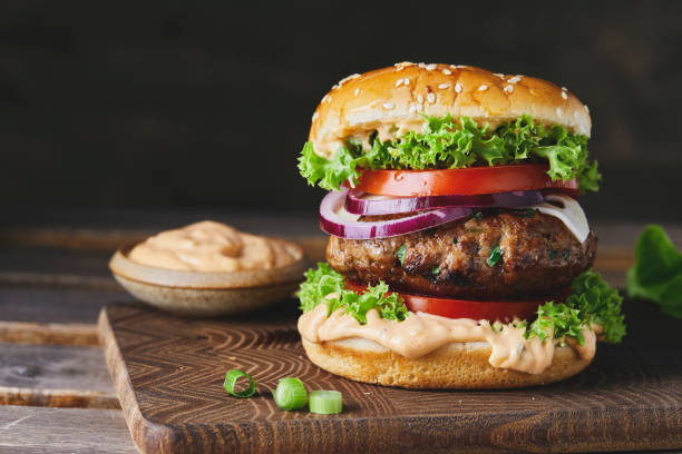 Hamburger on a handmade cutting board, dark mood background Beautiful and tasty hamburger on a handmade cutting board, dark mood background veggie burger stock pictures, royalty-free photos & images