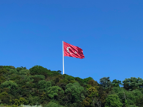 Turkish flag at mountain with clear blue sky.