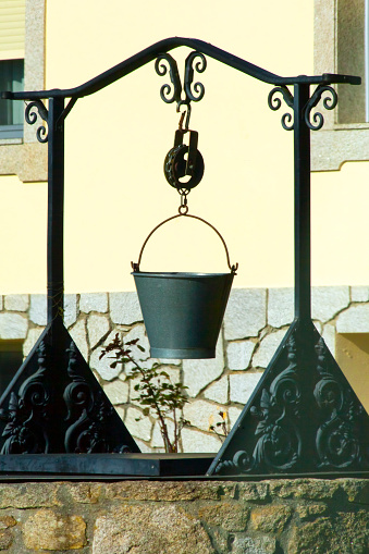 Old well pulley and bucket with a house facade background. Galicia, Spain.