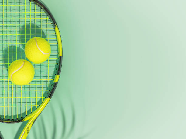 istock Racket with two yellow tennis balls with palm shadow 1412711428