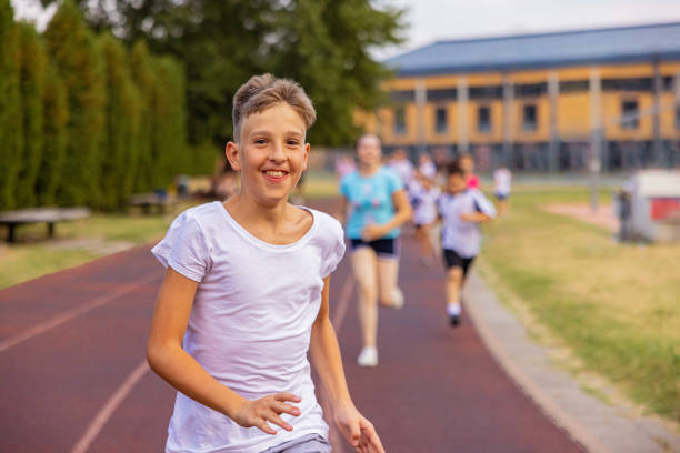 Close-up picture of four happy teenagers in sportswear holding a plank standing in a row  on the track outdoors
