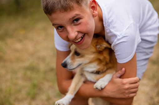 Young boy playing in backyard with his dog. They are hugging.
