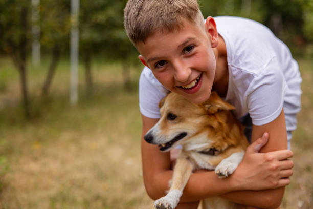 Young boy playing in backyard with his dog. They are hugging.