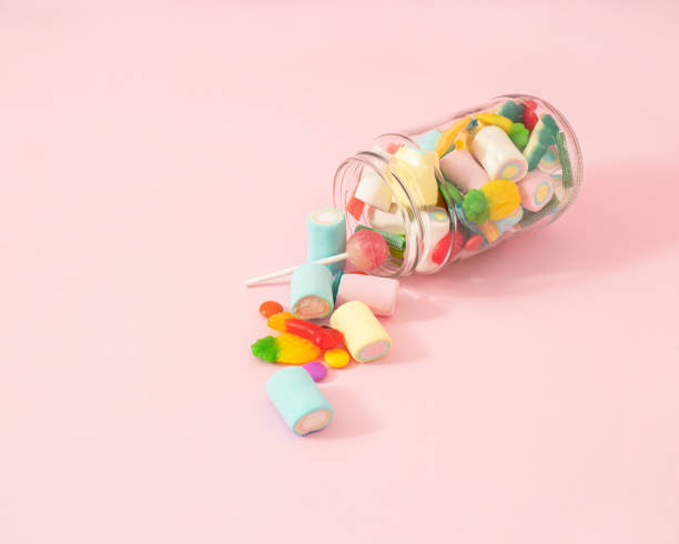 Creative concept of a glass jar full of delicious sweets from the candy store. Pastel pink background. Creative concept of a glass jar full of delicious sweets from the candy store. Pastel pink background. old candy store stock pictures, royalty-free photos & images