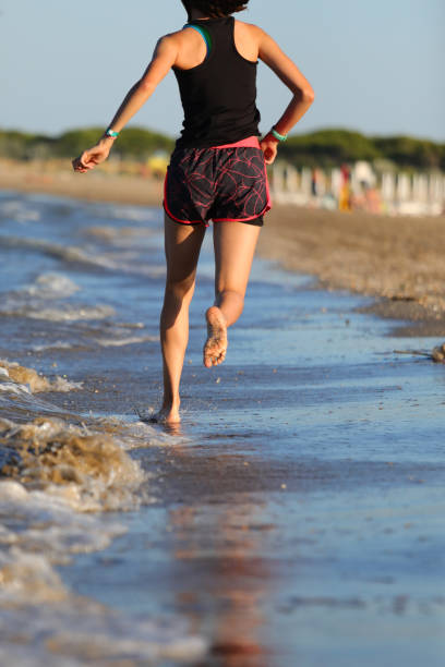 istock slender athletic young girl running barefoot on the seashore 1412712973