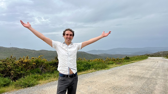 a handsome French or Spaniard man in a white shirt stands against the backdrop of mountains. High quality 4k footage