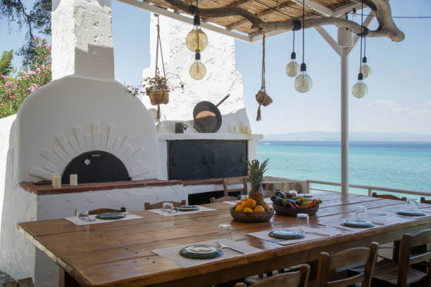 Big spacious wooden table and traditional Greek oven. Mediterranean restaurant interior style with sea view. stock photo