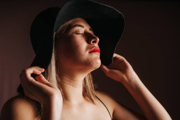 Unrecognizable woman wearing red dress picking accessories to her outfit holding big sun hat.