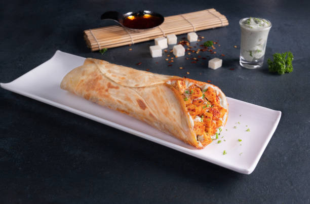 Paneer Tikka shawarma Wrap served in a cutting board on grey background side view of fastfood stock photo