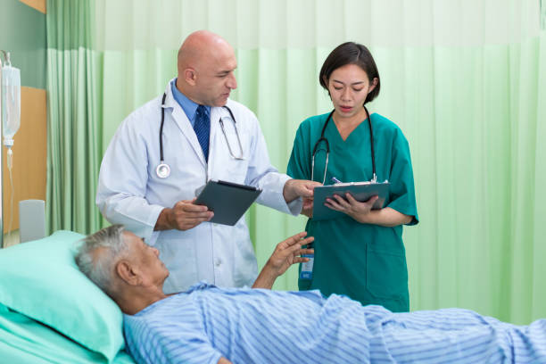 istock Doctor Visiting man Patient On Ward. Hospitalized man lying in bed while doctor checking his. physician examining male patient in hospital room. 1412718327