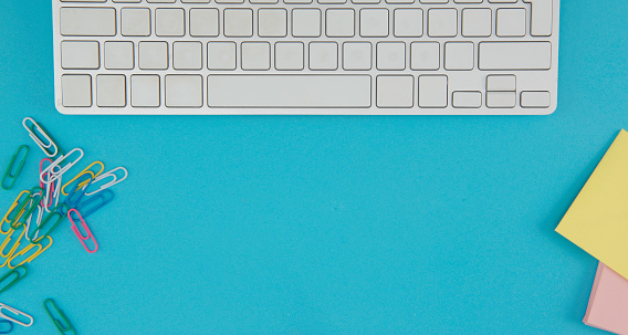 Woman typing with keyboard. Office supplies on blue background.