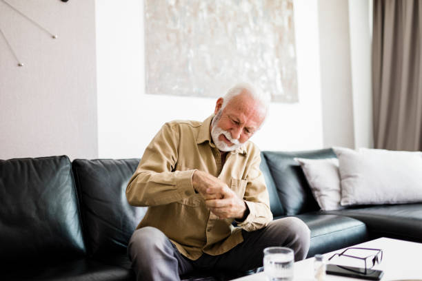 istock Senior man rubbing his hands in discomfort, suffering from arthritis in his hand while sitting on sofa at home. Elderly and health issues concept, Pain in the hands can be symptoms of carpal tunnel 1412725961