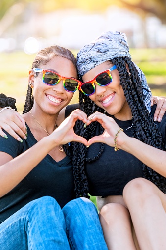 Afro-latinx young lesbians embracing sitting on the grass in a park